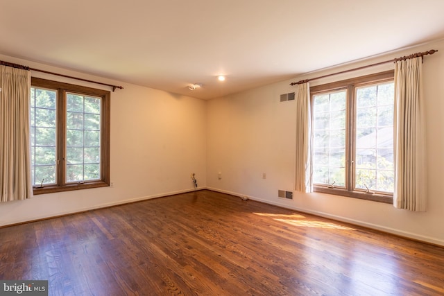 unfurnished room featuring dark hardwood / wood-style flooring and a wealth of natural light