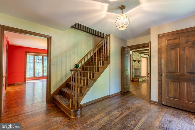 staircase with hardwood / wood-style flooring and a brick fireplace