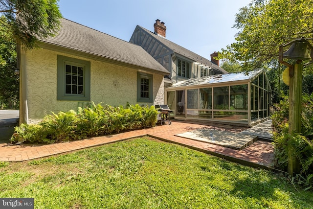 back of house featuring a patio area, a sunroom, and a lawn