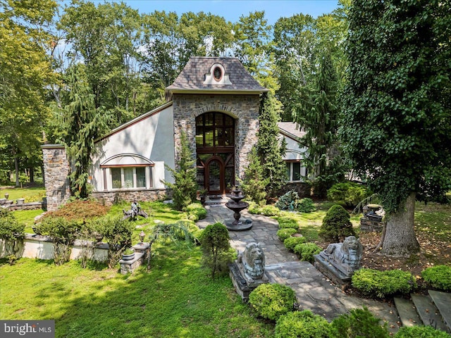 view of front of property featuring stone siding, a front lawn, french doors, and stucco siding