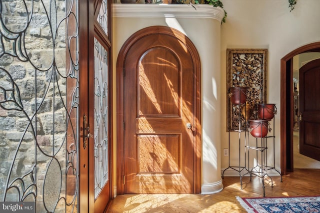 entryway featuring arched walkways, french doors, wood finished floors, and crown molding