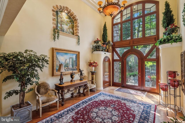 entryway featuring a chandelier, wood finished floors, a towering ceiling, and baseboards