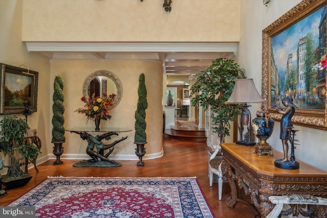 hallway featuring ornamental molding, arched walkways, baseboards, and wood finished floors