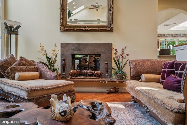 living area featuring ceiling fan, wood finished floors, and a high end fireplace