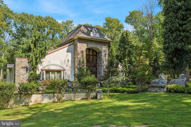 view of front facade featuring stone siding, a front lawn, and stucco siding