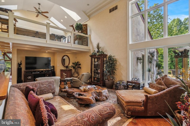 living area with a skylight, visible vents, plenty of natural light, and wood finished floors