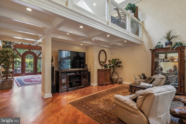 living area featuring coffered ceiling, beamed ceiling, baseboards, and wood finished floors