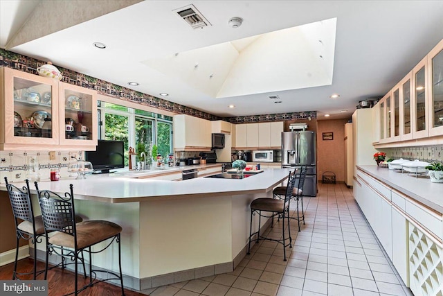 kitchen with a peninsula, visible vents, stainless steel appliances, and decorative backsplash