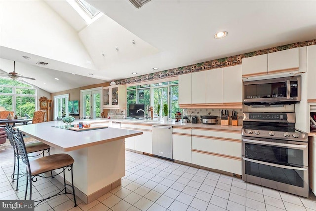 kitchen with visible vents, lofted ceiling with skylight, stainless steel appliances, light countertops, and a kitchen bar