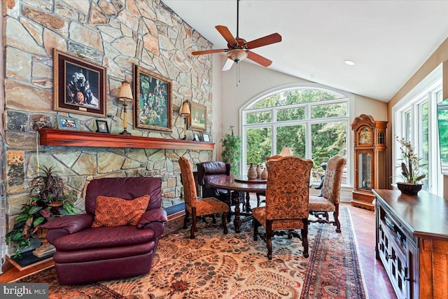 dining area with lofted ceiling, a fireplace, wood finished floors, and a ceiling fan