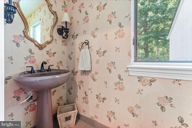 bathroom with baseboards, a healthy amount of sunlight, and wallpapered walls