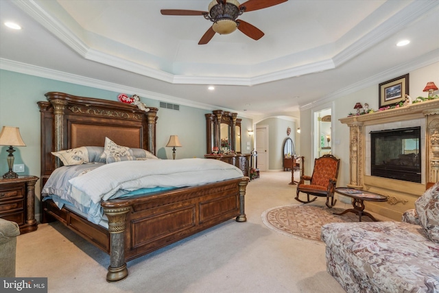 bedroom featuring arched walkways, a tile fireplace, light colored carpet, visible vents, and a tray ceiling