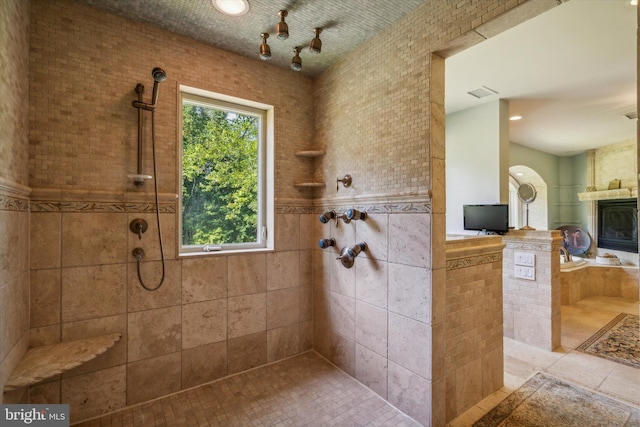 bathroom featuring visible vents, a walk in shower, and a glass covered fireplace