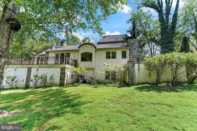 view of front of house featuring a chimney, a front yard, and stucco siding