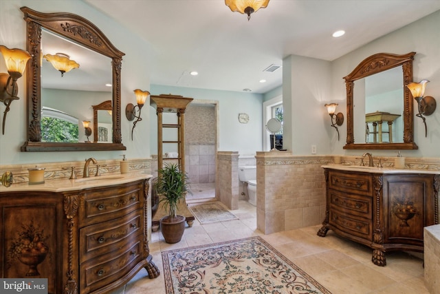 full bathroom featuring visible vents, two vanities, a sink, tile patterned flooring, and tile walls