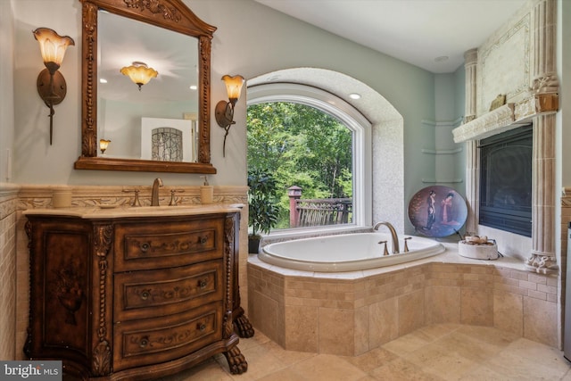 full bath featuring a garden tub, tile patterned floors, a fireplace, and vanity