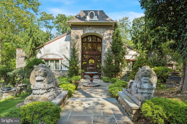 view of front of property with stone siding and a high end roof