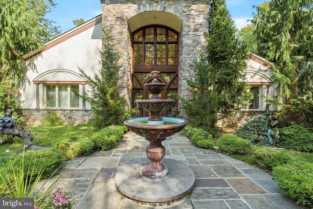 view of exterior entry with stone siding, french doors, and stucco siding