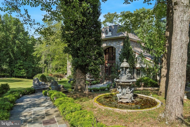 view of front facade featuring stone siding, a front yard, and a high end roof