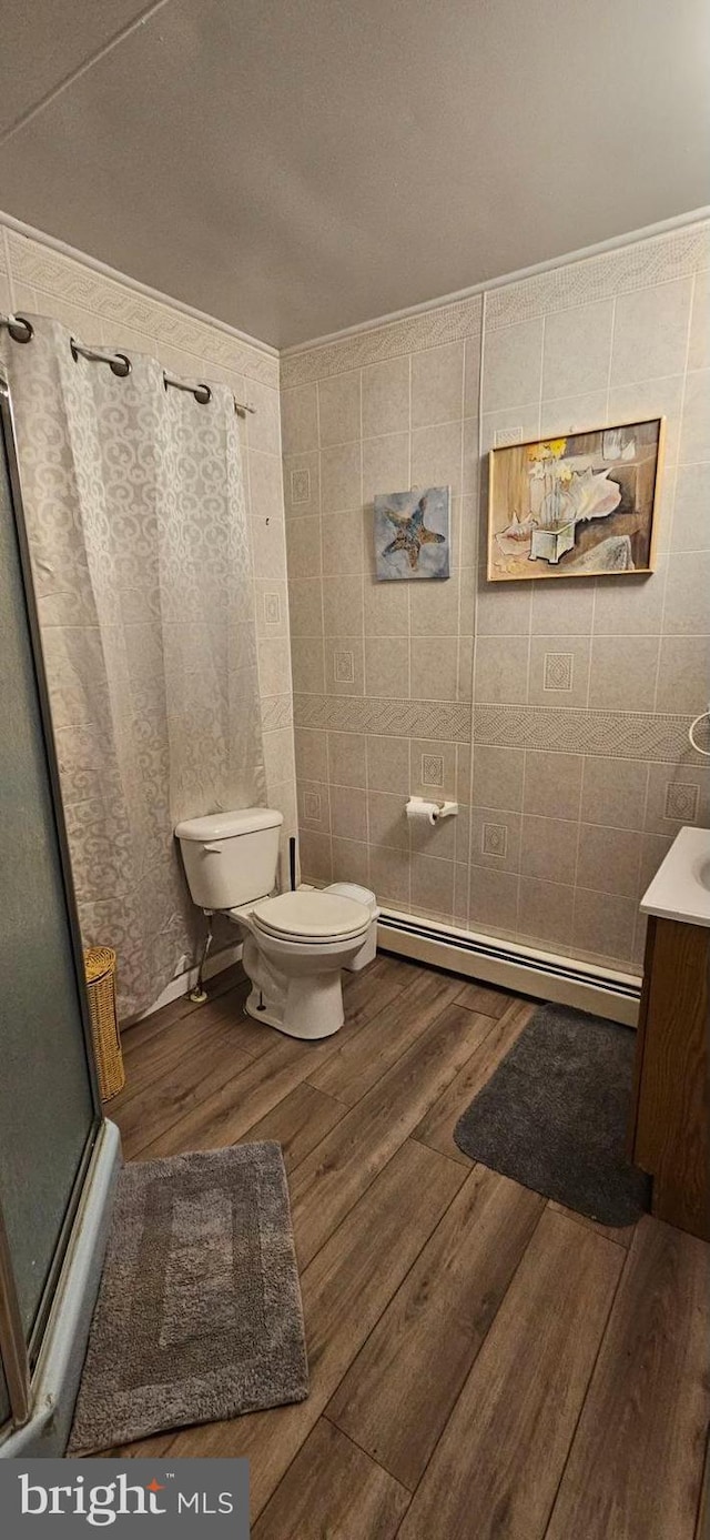 bathroom featuring toilet, baseboard heating, vanity, a shower with door, and hardwood / wood-style flooring