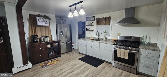 kitchen with sink, white cabinetry, stainless steel appliances, a baseboard radiator, and wall chimney exhaust hood