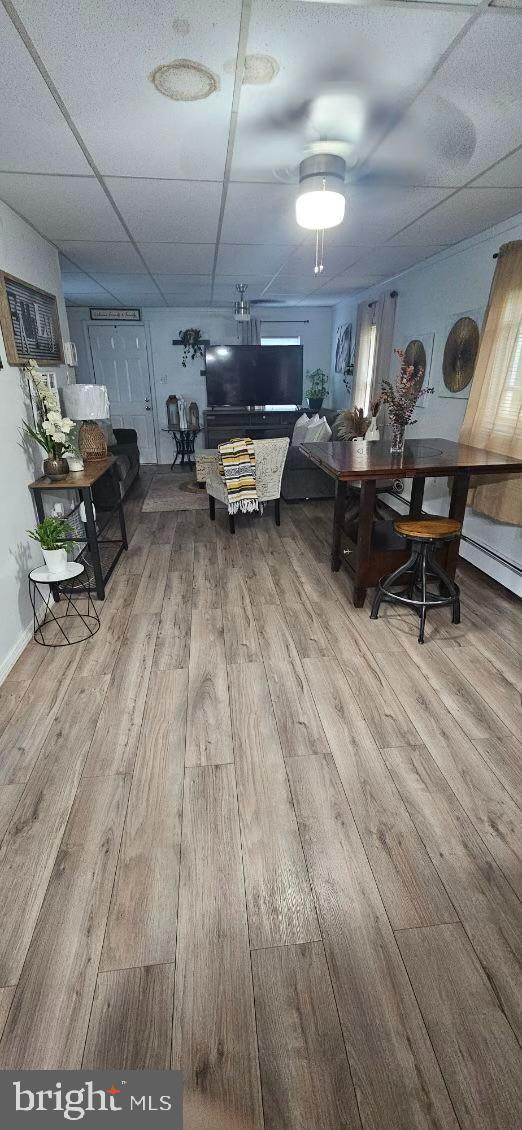 dining space featuring a baseboard heating unit, hardwood / wood-style floors, and a drop ceiling