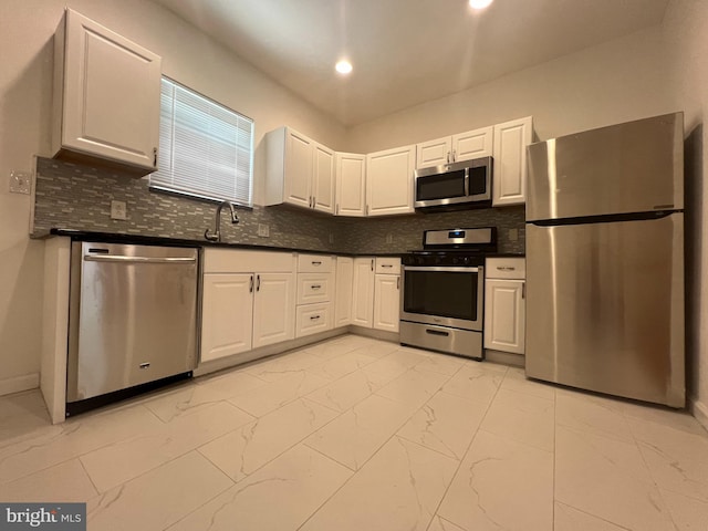 kitchen with white cabinets, stainless steel appliances, sink, and tasteful backsplash