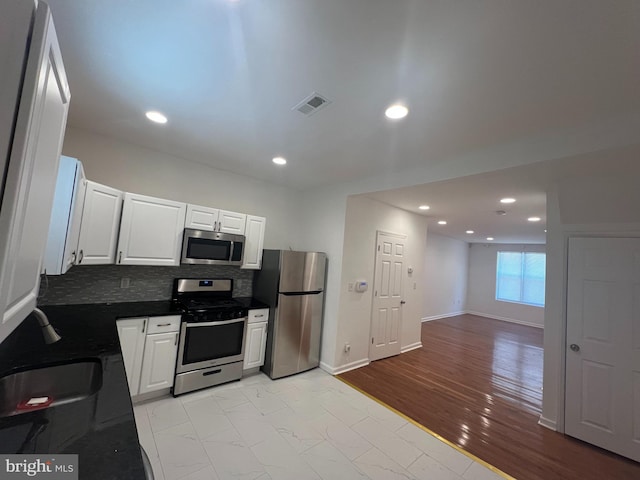 kitchen with backsplash, appliances with stainless steel finishes, sink, and white cabinetry