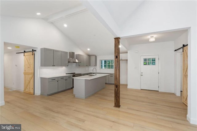 kitchen with light hardwood / wood-style floors, a barn door, and wall chimney range hood