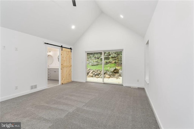 unfurnished bedroom with carpet floors, access to exterior, connected bathroom, a barn door, and high vaulted ceiling