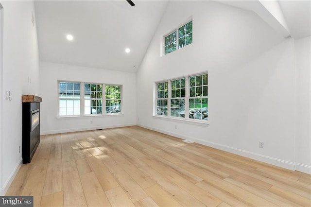 unfurnished living room featuring high vaulted ceiling and light hardwood / wood-style floors