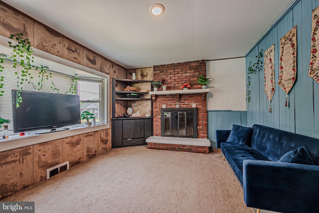 carpeted living room with a fireplace, wood walls, and brick wall