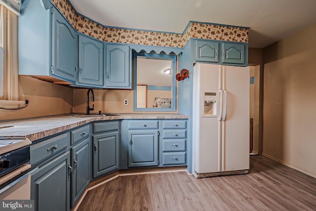 kitchen featuring light wood-type flooring, blue cabinets, range with electric cooktop, white refrigerator with ice dispenser, and sink