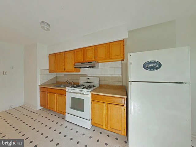 kitchen featuring white appliances, tasteful backsplash, and sink