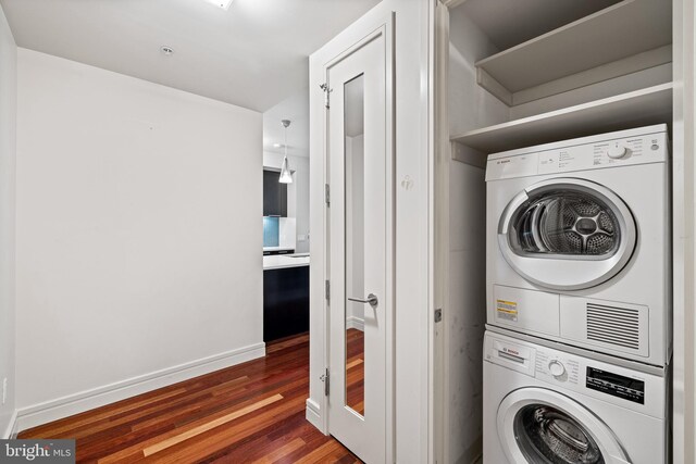 laundry area featuring stacked washer / drying machine and dark hardwood / wood-style floors