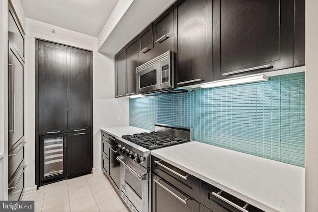 kitchen with appliances with stainless steel finishes, wine cooler, backsplash, light stone countertops, and light tile patterned floors