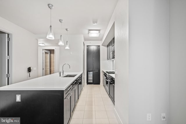 kitchen featuring appliances with stainless steel finishes, sink, light tile patterned floors, and decorative light fixtures