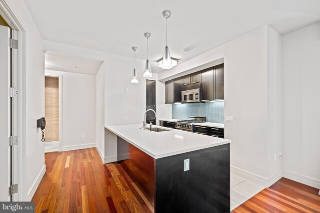 kitchen with stainless steel appliances, kitchen peninsula, hardwood / wood-style floors, and sink