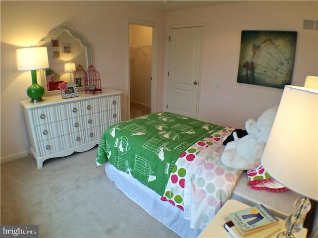 carpeted bedroom with a closet, visible vents, and a walk in closet