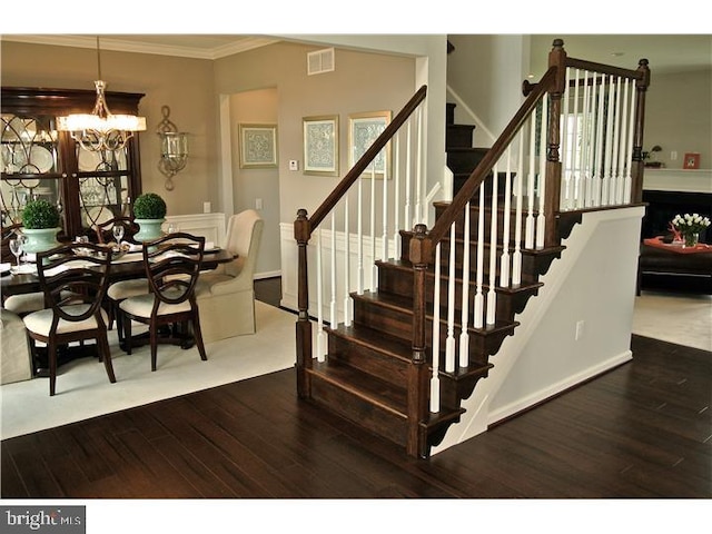 stairs with hardwood / wood-style flooring, an inviting chandelier, and crown molding