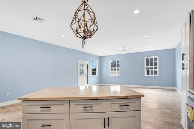 kitchen with light stone counters, hanging light fixtures, a center island, and white cabinets