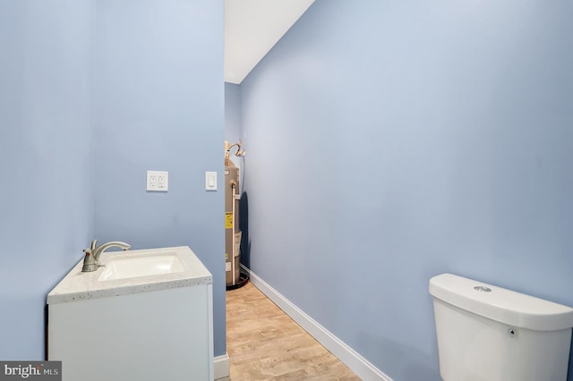 bathroom with vanity, hardwood / wood-style flooring, water heater, and toilet