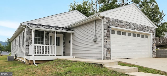 view of front of home featuring cooling unit, a garage, a front lawn, and covered porch