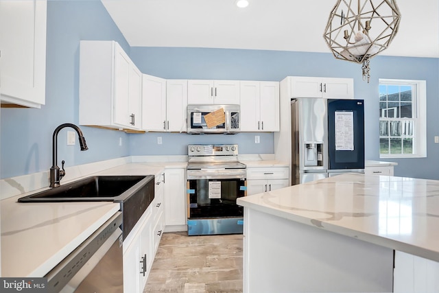 kitchen with appliances with stainless steel finishes, decorative light fixtures, light stone countertops, and white cabinets