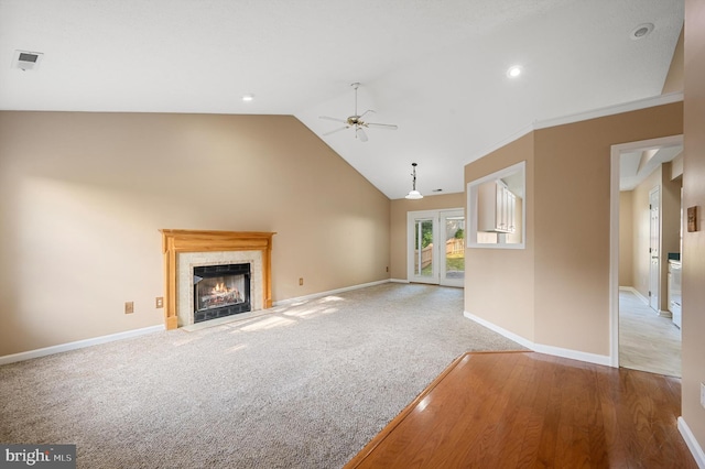 unfurnished living room featuring lofted ceiling, ceiling fan, a tile fireplace, and light hardwood / wood-style floors