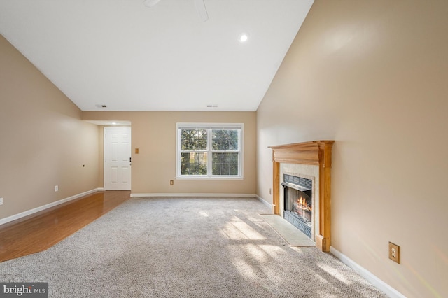 unfurnished living room with a tile fireplace, vaulted ceiling, and light hardwood / wood-style flooring