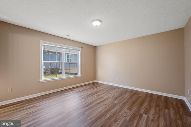 spare room featuring a textured ceiling and hardwood / wood-style floors