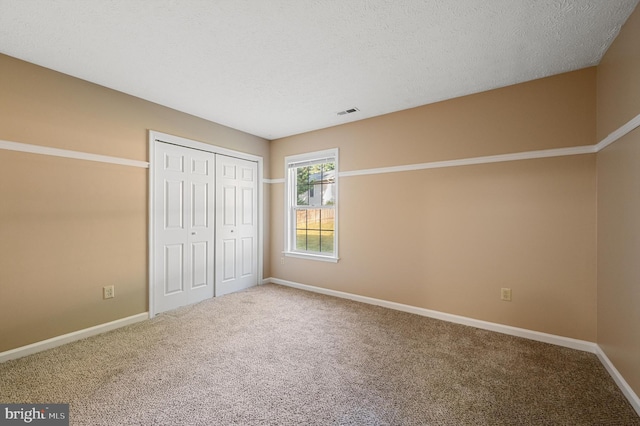 unfurnished bedroom featuring a textured ceiling, a closet, and carpet flooring