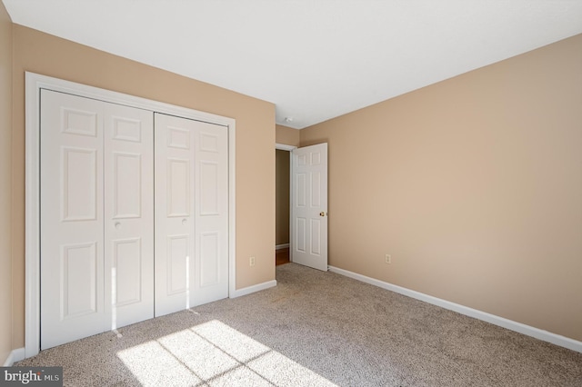 unfurnished bedroom with light colored carpet and a closet