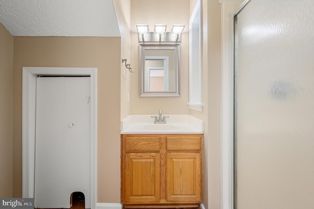 bathroom with a textured ceiling, vanity, and a shower with shower door